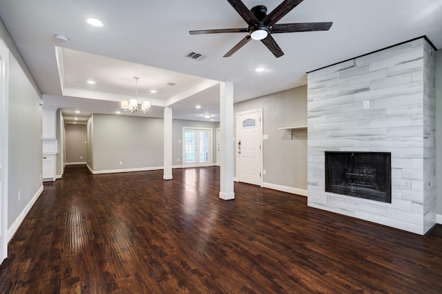 unfurnished living room featuring a tile fireplace, ceiling fan with notable chandelier, dark hardwood / wood-style floors, and a tray ceiling