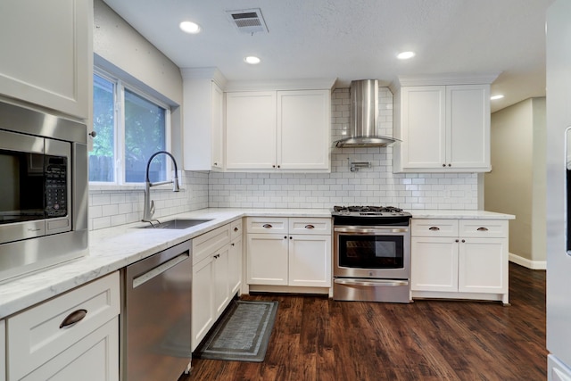 kitchen with white cabinetry, sink, wall chimney range hood, and appliances with stainless steel finishes