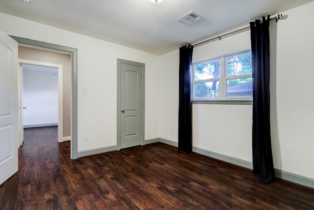 unfurnished bedroom featuring a textured ceiling and dark hardwood / wood-style floors