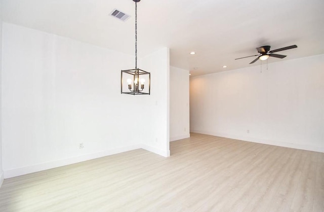 unfurnished room with ceiling fan with notable chandelier and light hardwood / wood-style floors