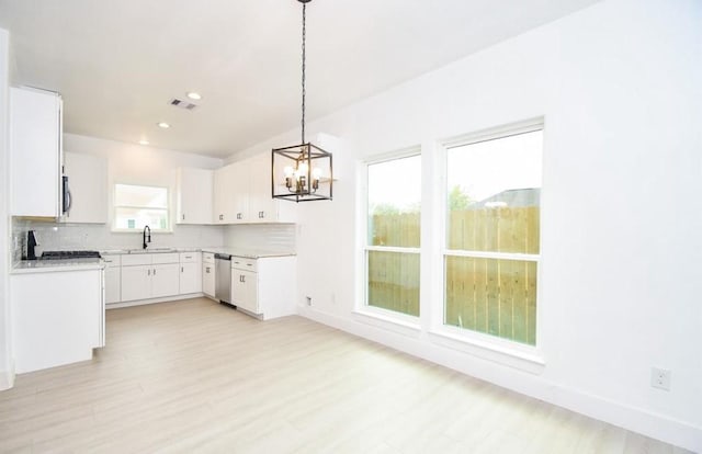 kitchen with stainless steel appliances, backsplash, hanging light fixtures, a wealth of natural light, and white cabinets