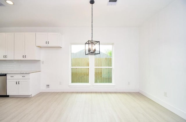 unfurnished dining area with a notable chandelier and light hardwood / wood-style flooring