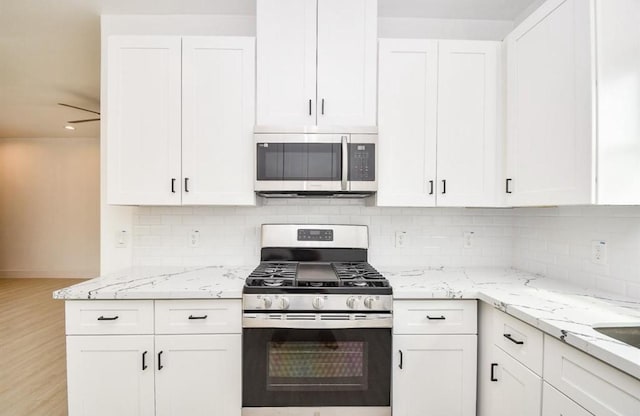 kitchen with ceiling fan, appliances with stainless steel finishes, tasteful backsplash, light stone countertops, and white cabinets