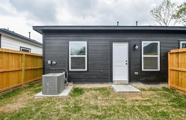 back of property featuring central AC and a yard