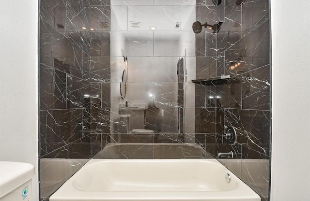 bathroom with tiled shower / bath combo and toilet