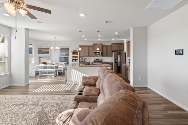 living room featuring wood-type flooring, sink, and ceiling fan with notable chandelier