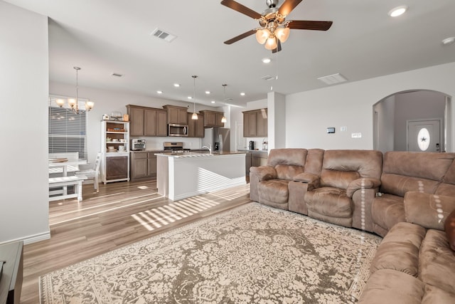 living room featuring ceiling fan with notable chandelier and light hardwood / wood-style flooring