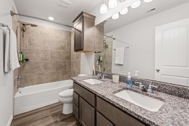 full bathroom featuring wood-type flooring, toilet, vanity, and tiled shower / bath