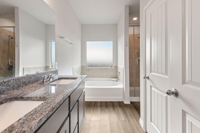 bathroom featuring plus walk in shower, wood-type flooring, and vanity