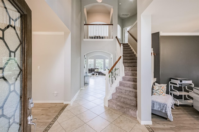 entryway with light tile patterned floors and ornamental molding