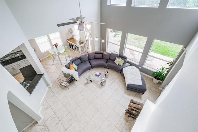 living room featuring ceiling fan, a towering ceiling, and light tile patterned flooring