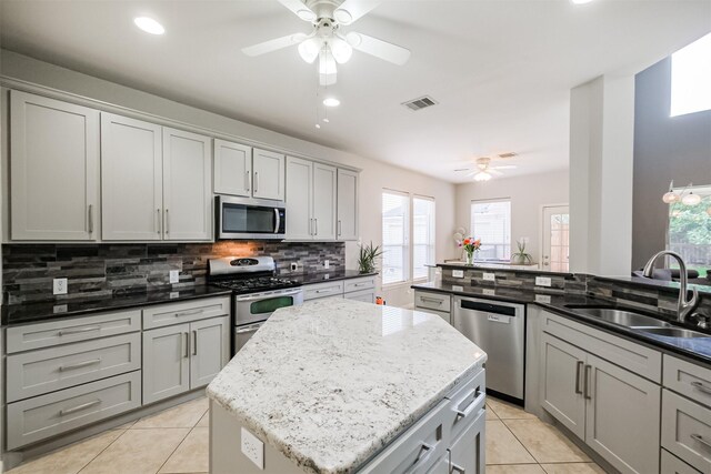 kitchen with sink, appliances with stainless steel finishes, dark stone counters, and a kitchen island