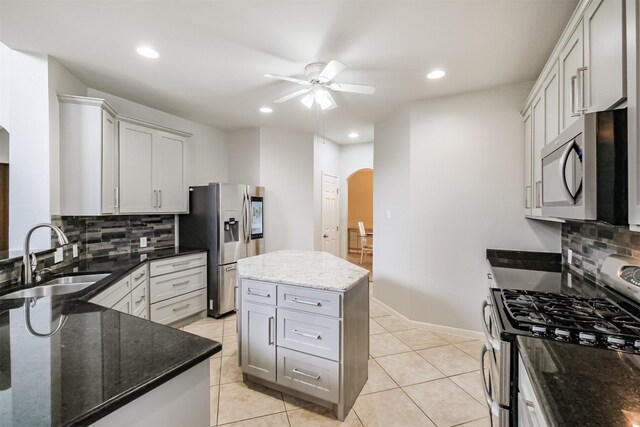 kitchen with tasteful backsplash, ceiling fan, sink, appliances with stainless steel finishes, and dark stone counters