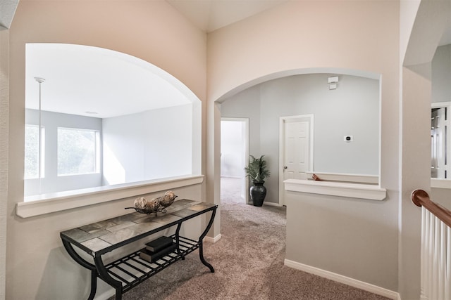 corridor with carpet floors and lofted ceiling