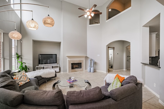 tiled living room featuring ceiling fan and a high ceiling