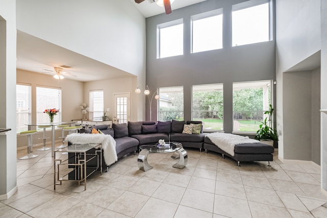 tiled living room featuring ceiling fan, a high ceiling, and a wealth of natural light