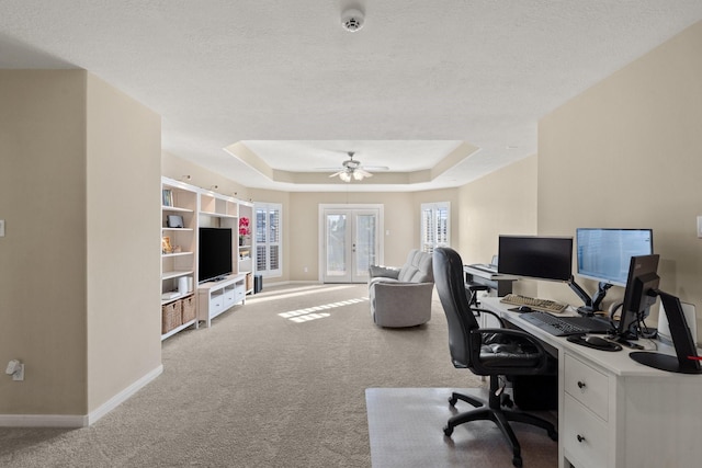 carpeted home office with french doors, ceiling fan, a textured ceiling, and a raised ceiling