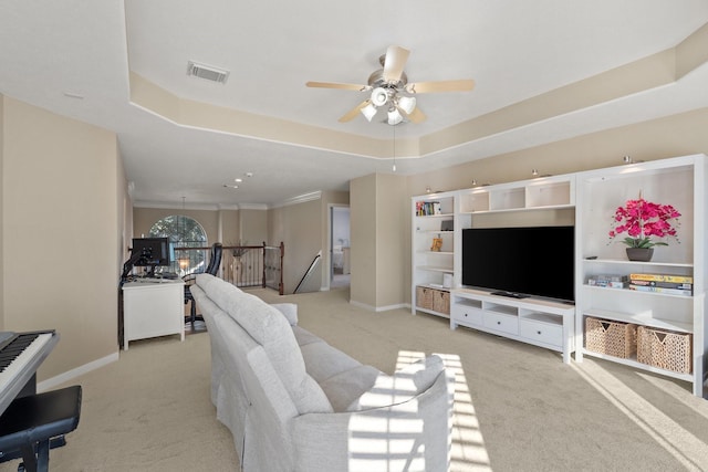 living room with a raised ceiling, light carpet, and ceiling fan