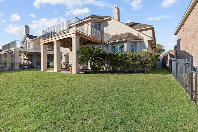 rear view of house featuring a balcony, a patio area, and a lawn