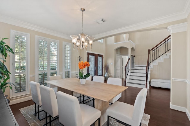 dining space with dark wood-type flooring, ornamental molding, french doors, and an inviting chandelier