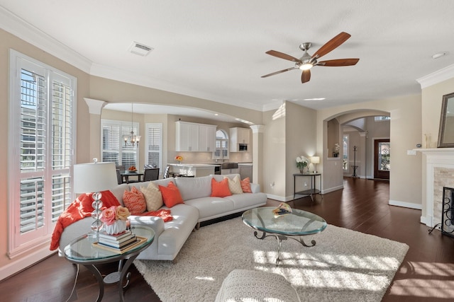 living room featuring a wealth of natural light, dark wood-type flooring, a tile fireplace, and crown molding