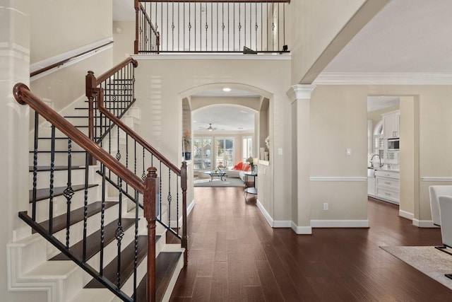 foyer entrance featuring ceiling fan, sink, dark hardwood / wood-style floors, ornamental molding, and decorative columns