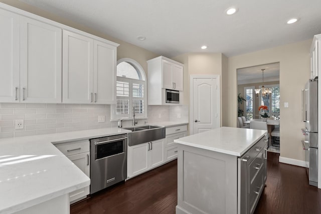 kitchen featuring white cabinetry, stainless steel appliances, a notable chandelier, pendant lighting, and a center island