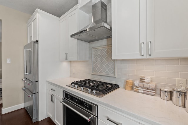 kitchen featuring backsplash, white cabinetry, a textured ceiling, stainless steel appliances, and wall chimney exhaust hood