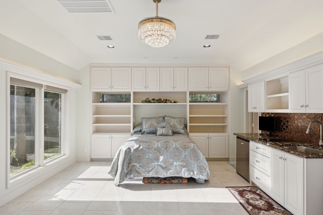 bedroom with light tile patterned flooring, vaulted ceiling, sink, and an inviting chandelier