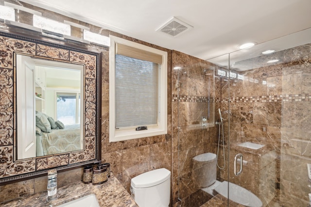 bathroom with tile walls, toilet, a shower with door, and vanity