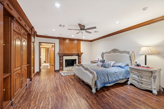 bedroom featuring ceiling fan, crown molding, dark hardwood / wood-style flooring, and a fireplace