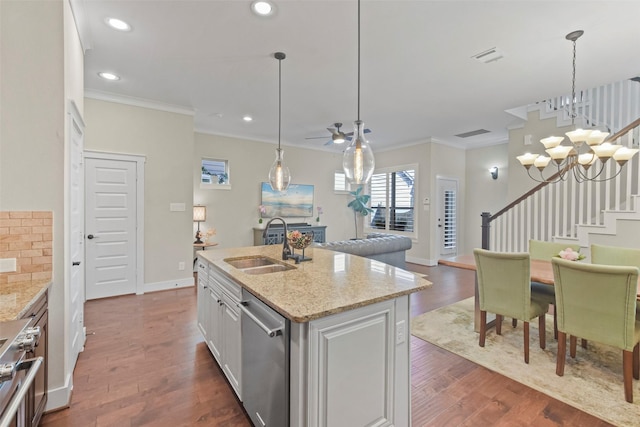 kitchen featuring light stone countertops, white cabinets, appliances with stainless steel finishes, ornamental molding, and a center island with sink