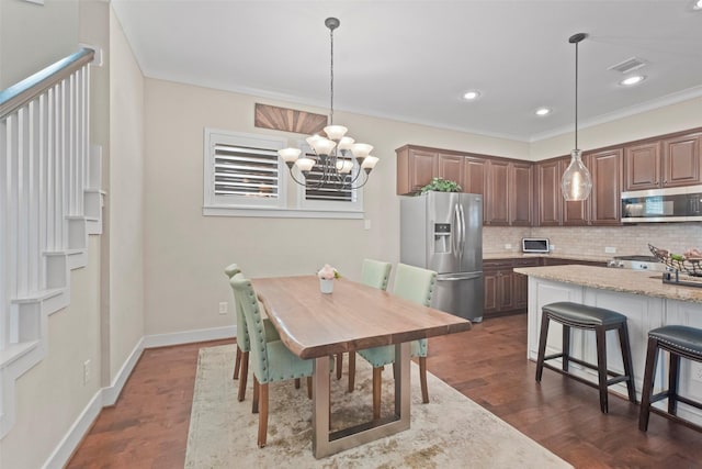 dining space with dark hardwood / wood-style flooring, ornamental molding, and an inviting chandelier