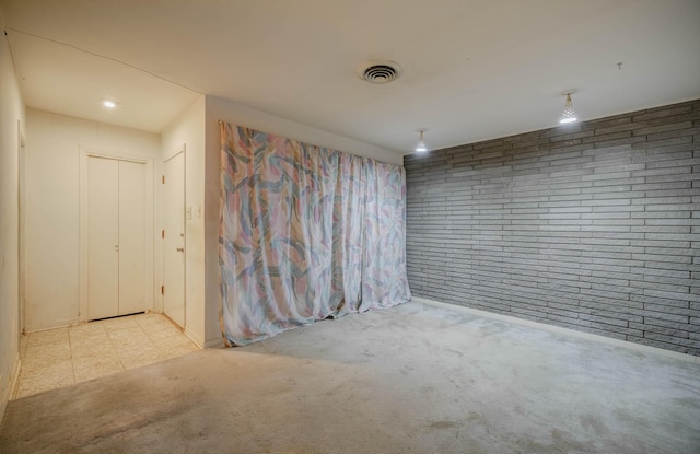 empty room featuring light carpet and brick wall