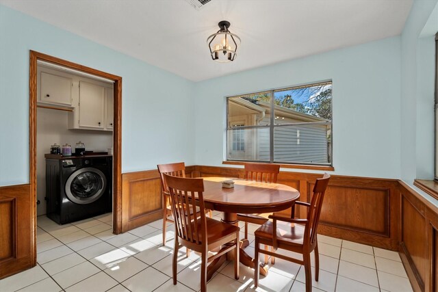 dining area featuring light tile patterned floors, an inviting chandelier, washer and dryer, and wooden walls