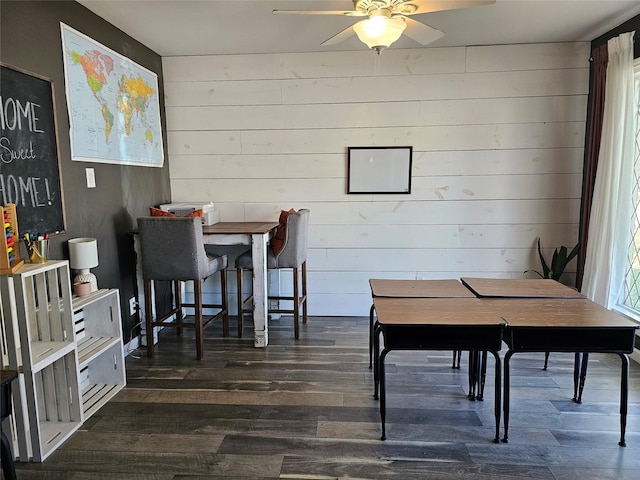 dining space with ceiling fan, wooden walls, and dark hardwood / wood-style floors