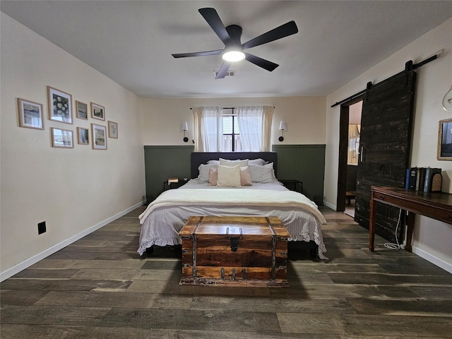 bedroom featuring dark hardwood / wood-style floors, ceiling fan, and a barn door