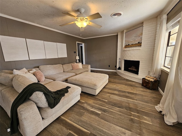 living room featuring ceiling fan, dark hardwood / wood-style flooring, a brick fireplace, and a textured ceiling