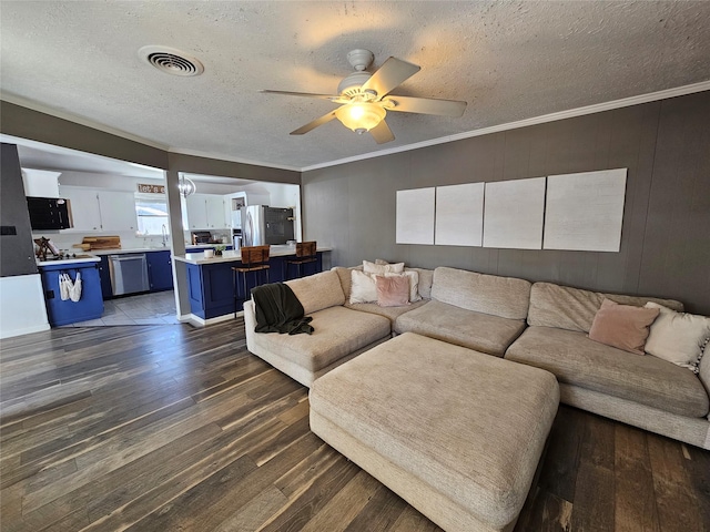 living room with ceiling fan, ornamental molding, dark hardwood / wood-style flooring, and a textured ceiling