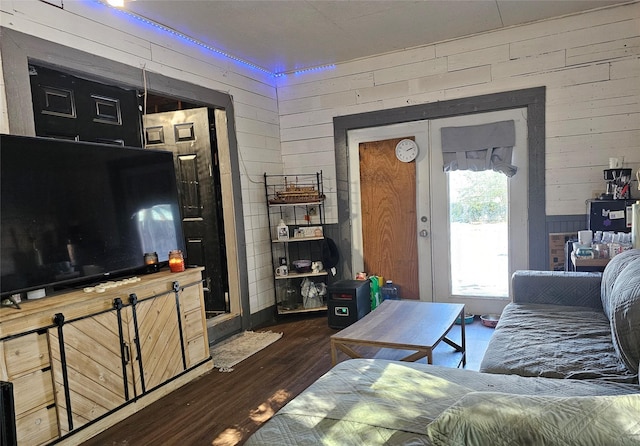 living room with dark hardwood / wood-style floors, french doors, and wooden walls