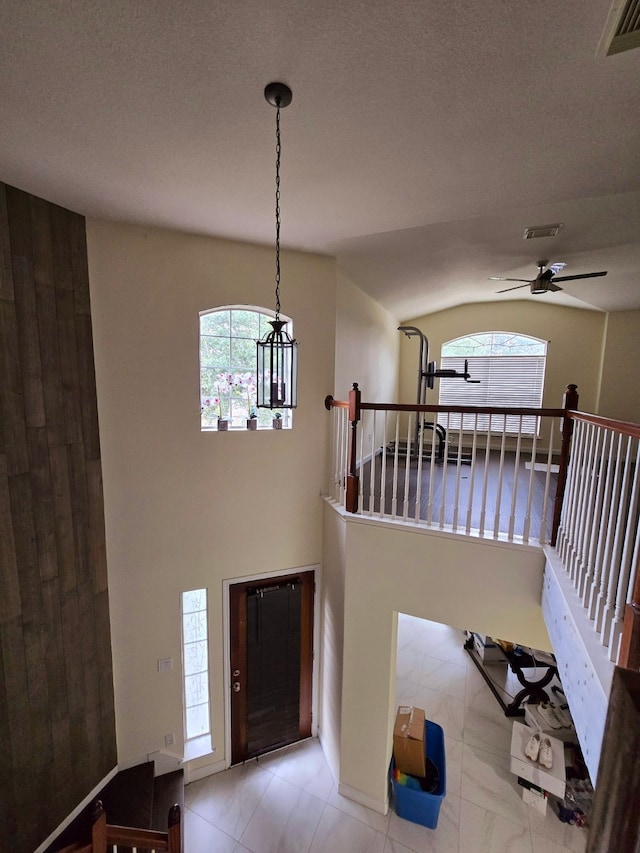 entryway featuring ceiling fan, lofted ceiling, and light tile patterned flooring