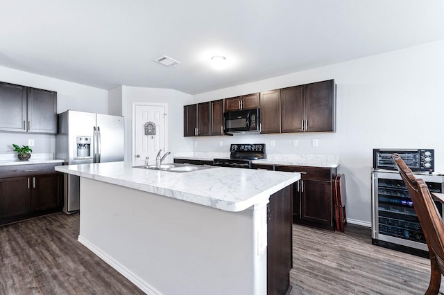 kitchen with wine cooler, black appliances, sink, an island with sink, and dark brown cabinets