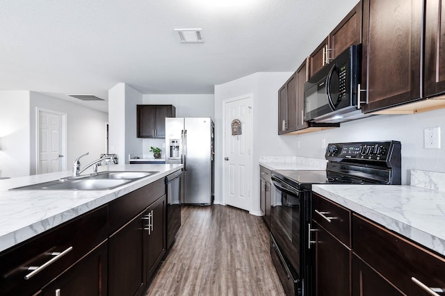 kitchen with hardwood / wood-style floors, a textured ceiling, black appliances, dark brown cabinetry, and sink