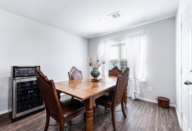 dining space featuring beverage cooler and hardwood / wood-style flooring