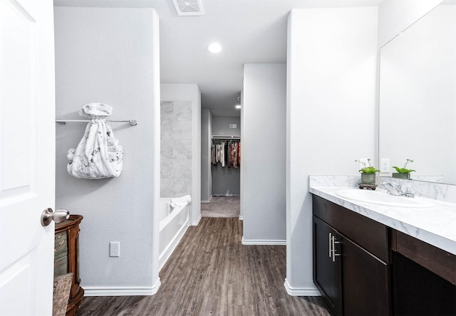 bathroom featuring washtub / shower combination, wood-type flooring, and vanity