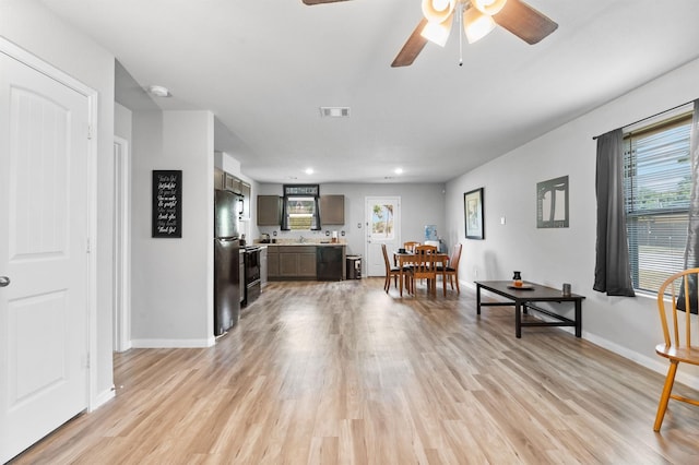 living room with ceiling fan, light hardwood / wood-style floors, plenty of natural light, and sink