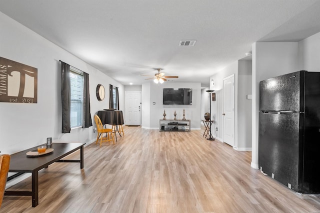 living room featuring a textured ceiling, ceiling fan, and light hardwood / wood-style flooring