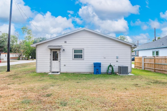 back of house with cooling unit and a yard