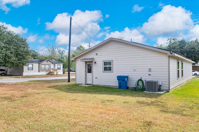 rear view of property featuring a lawn and central air condition unit