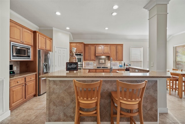 kitchen with an island with sink, appliances with stainless steel finishes, and a breakfast bar